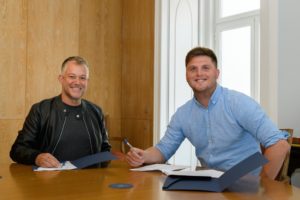 David Nicol Williams, CEO of NomadX (L), and Radim Rezek, CEO of Flatio, signing a merger deal (Photo credit: NomadX/LinkedIn)